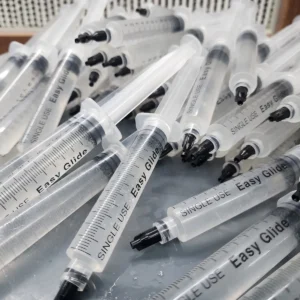 100 pack spore syringe bundle of syringe laid out on a table in a pile.
