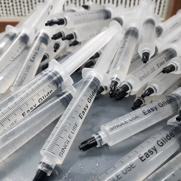 100 pack spore syringe bundle of syringe laid out on a table in a pile.