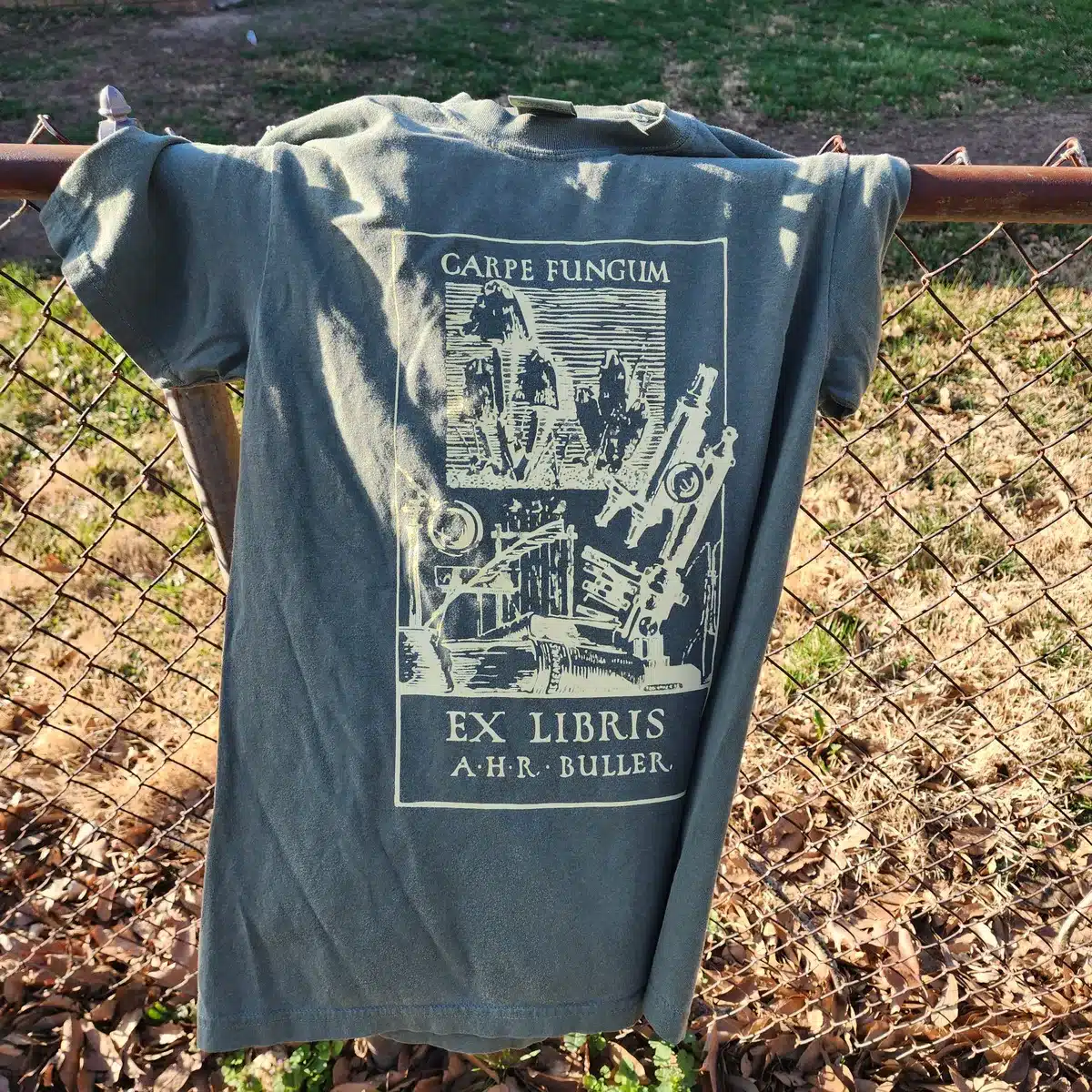 Detailed close-up of the green Carpe Fungum shirt highlighting the yellow fungal artwork on high-quality cotton fabric.