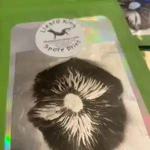 Lizard King Psilocybe cubensis spore print showing dark brown to purple-black deposit pattern.