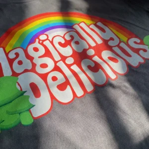 Grey short with a mock logo of a popular cereal brand. Says magically delicious with little green shamrock basidium Logos