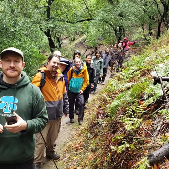 Alan Rockefeller leading a forage through the woods on the hunt for mushrooms with foragers in tail.