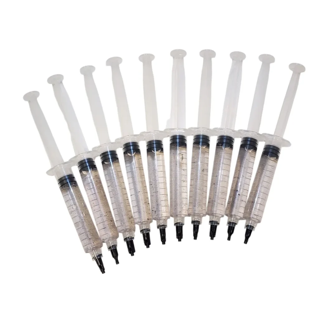 Spore Syringes in a line of ten. Displaying the clear fluid with dark spores suspended in the water.