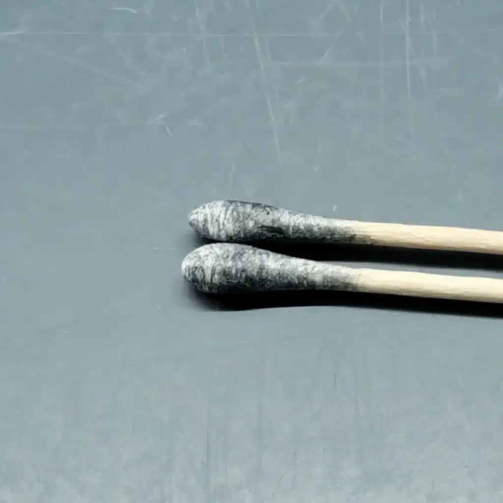 Pair of cotton Spore swabs with blue-black spore deposits visible on the tips.