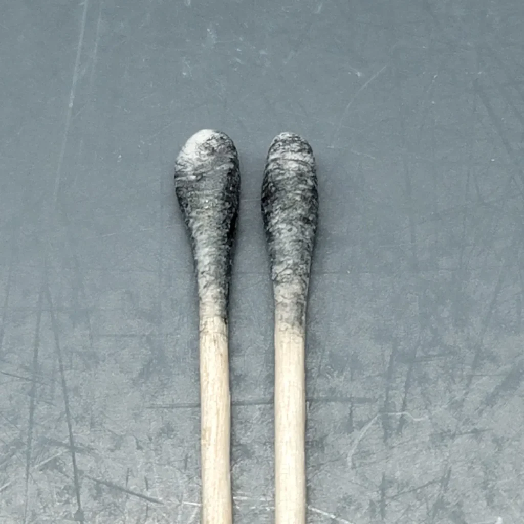 Two cotton swabs that are a blueish black on the tips with spores.